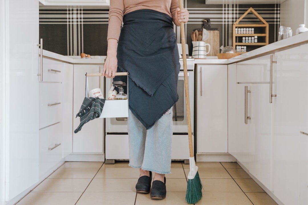 a woman standing in a kitchen holding a broom - eco-friendly cleaning service